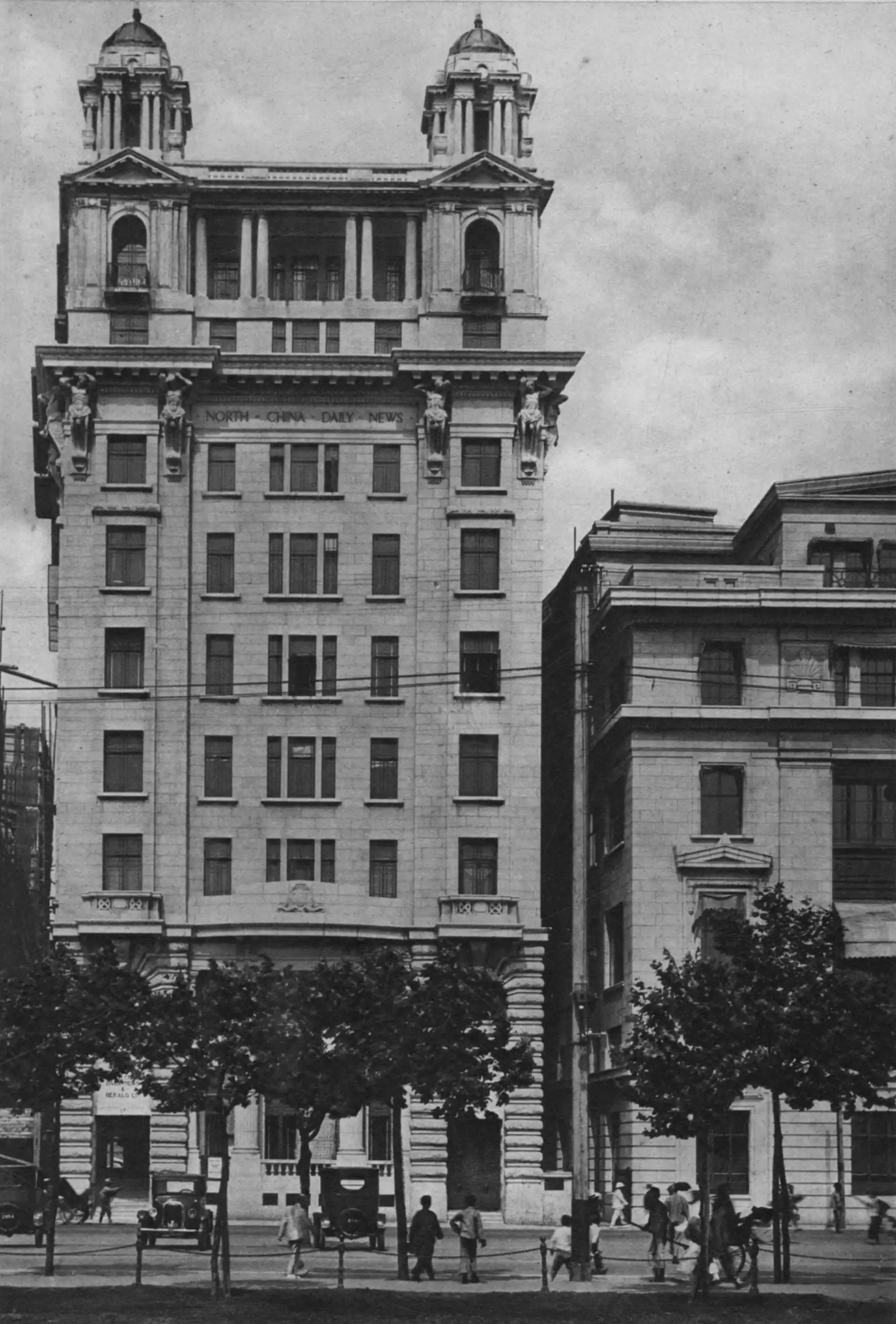 The North China Daily News building, a tall stone office block with twin turrets, in a plate from the 1927 book Shanghai of Today.