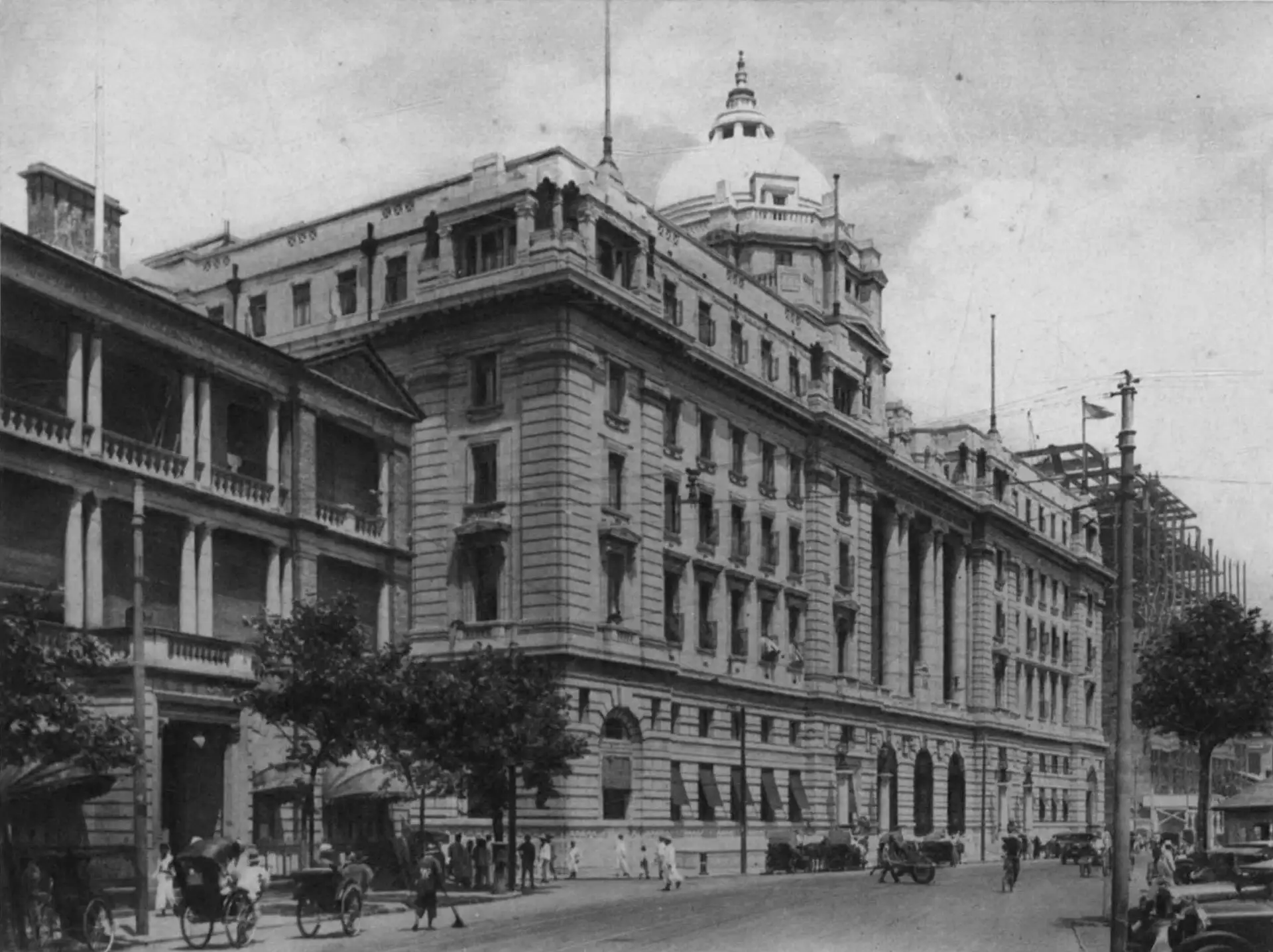 The HSBC Building with its dome, seen along the Bund with carts and cars in the street, in a plate from the 1927 book Shanghai of Today.