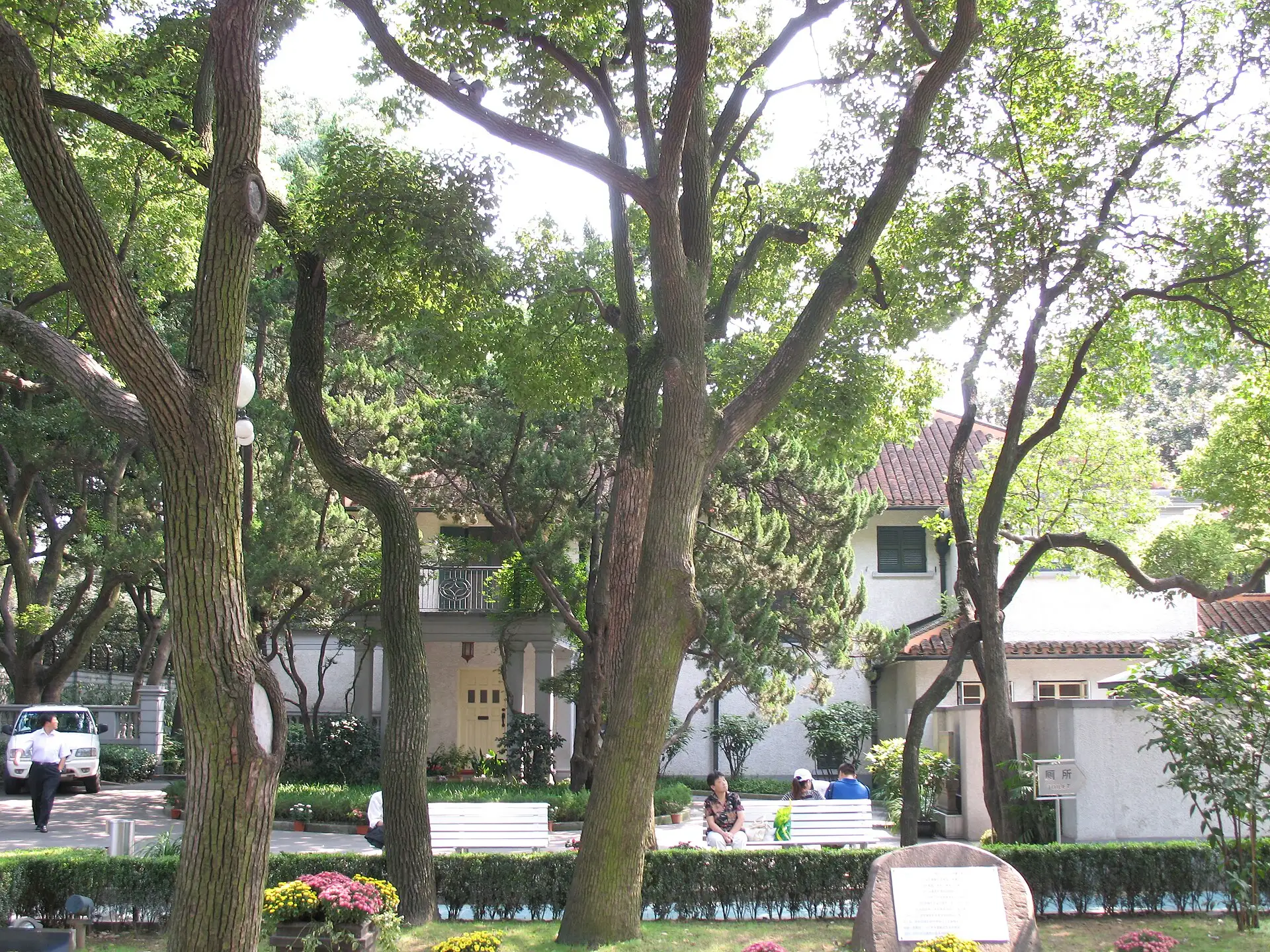The garden of Soong Ching-ling's former residence: a lawn and tall trees, with the white house behind.