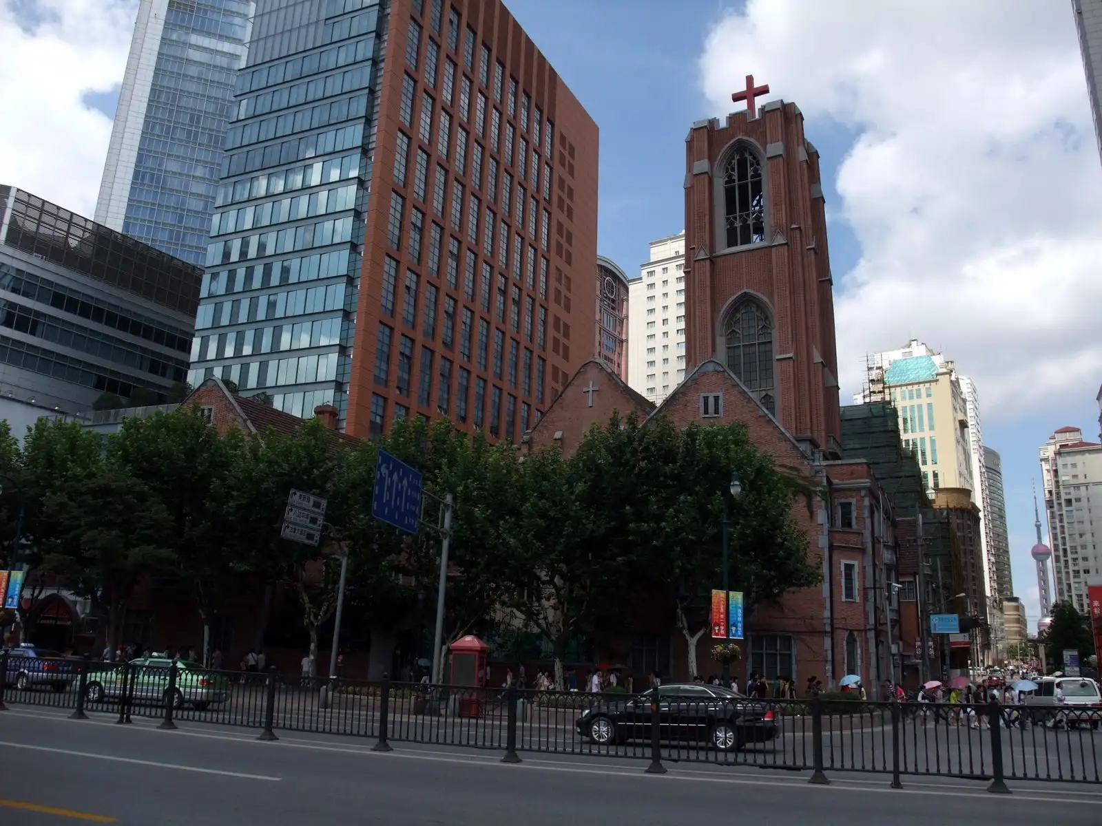 Moore Memorial Church's red-brick tower with a cross, among taller modern buildings on Xizang Road.