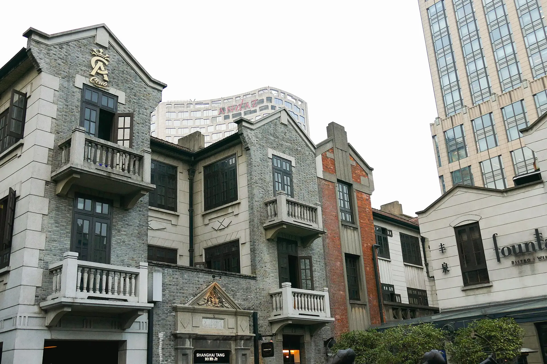 Restored shikumen houses with grey brick walls and stone gateways around a plaza in Xintiandi.