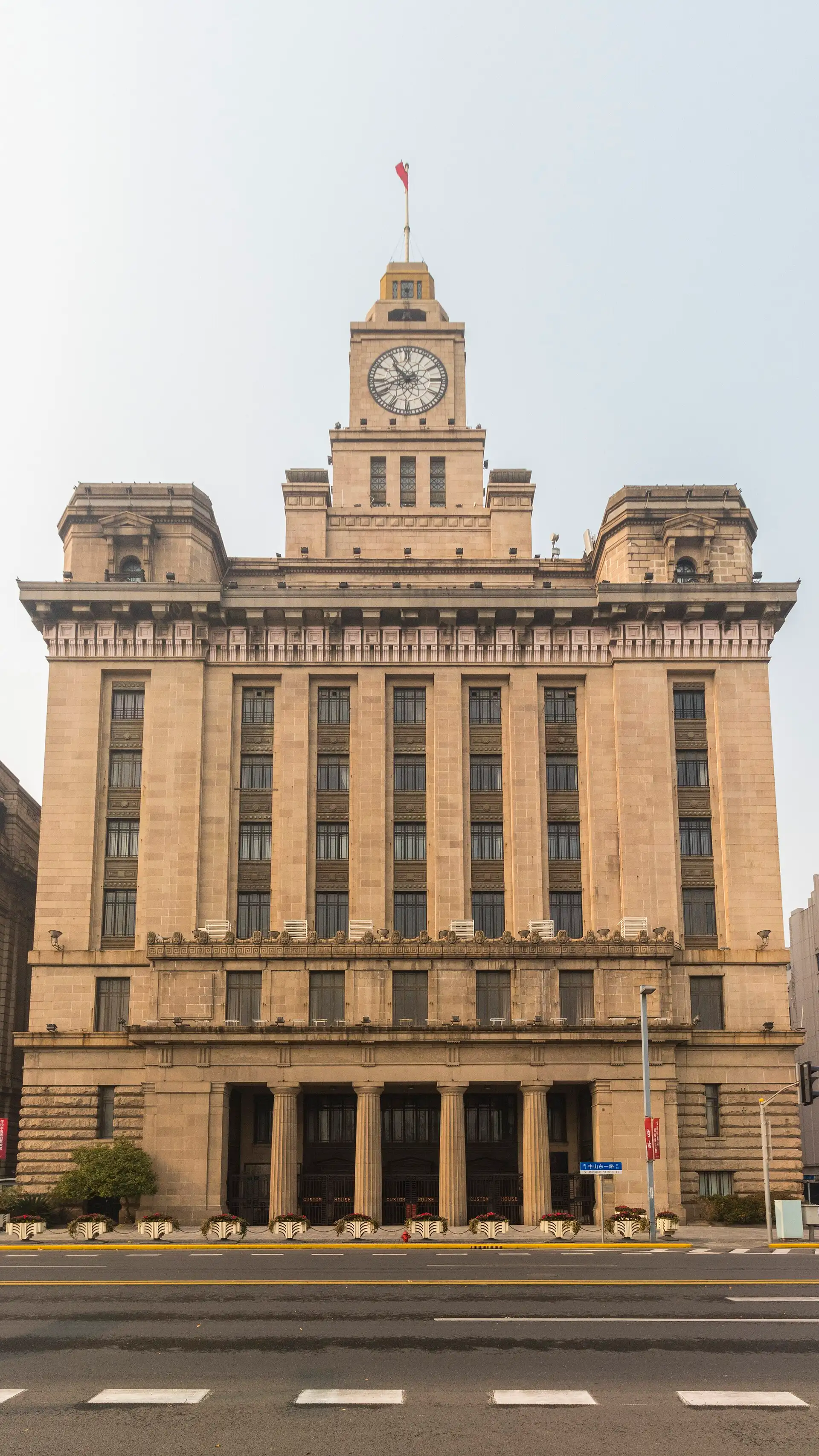 The Customs House seen head-on from the Bund: a granite tower with the clock face above a row of Doric columns.