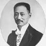 Black-and-white oval portrait of a smiling man with a moustache in evening dress with a white bow tie and a decoration.