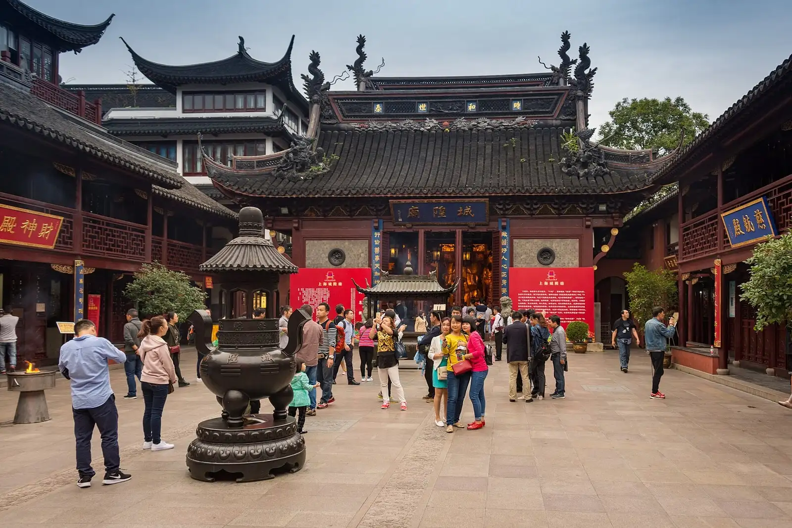Visitors in the courtyard of Shanghai City God Temple, with an incense burner and tiled temple halls.