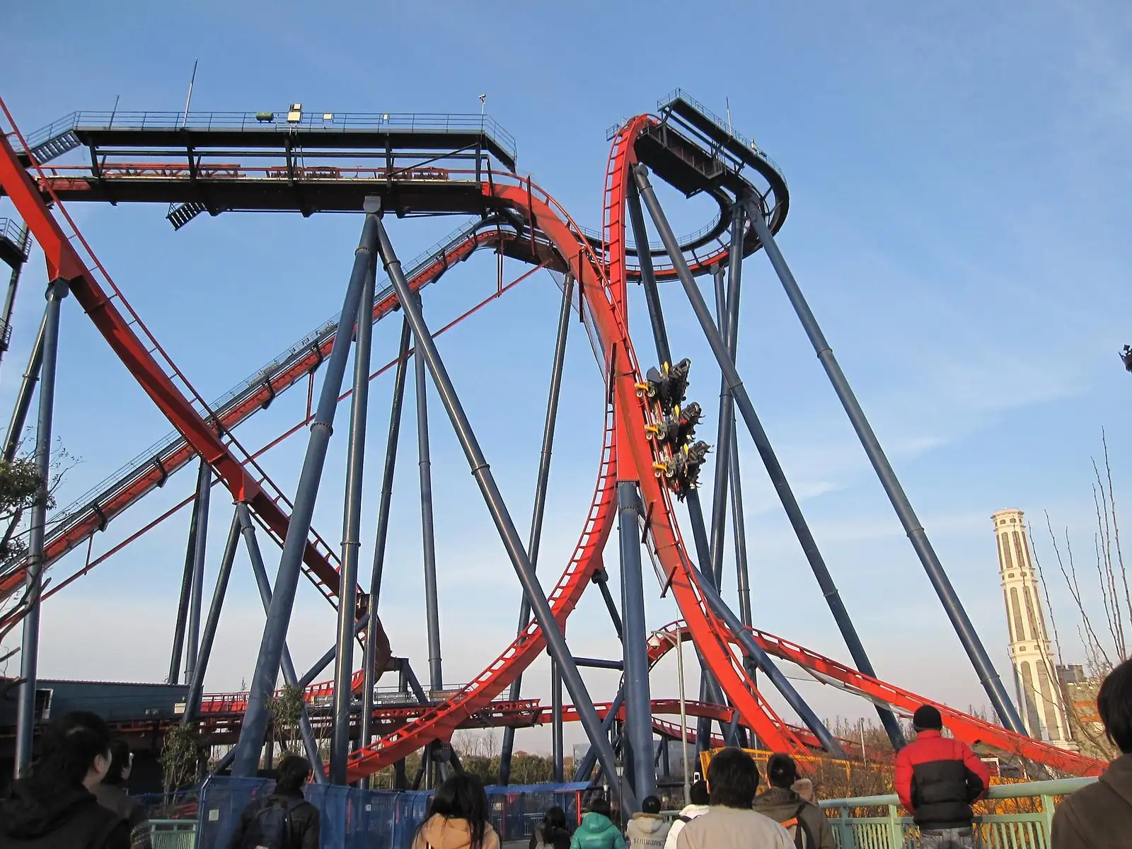 Red roller-coaster tracks twisting above visitors at Happy Valley Shanghai.