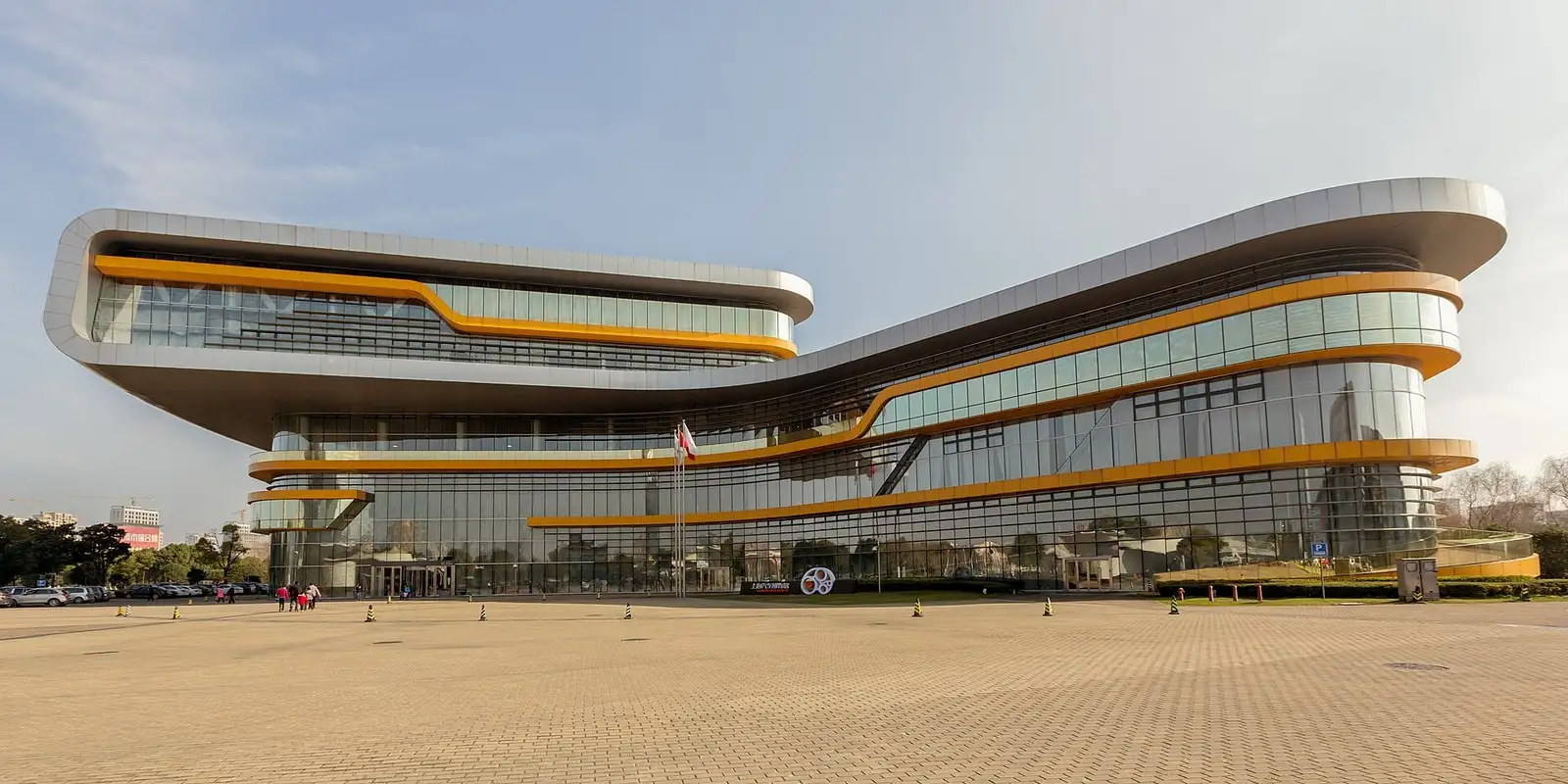 The curved facade of Shanghai Auto Museum, with long horizontal window bands and a wide forecourt.