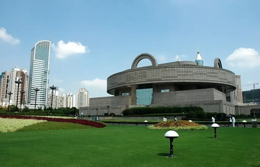 Shanghai Museum's round upper building and roof handles above a green lawn.