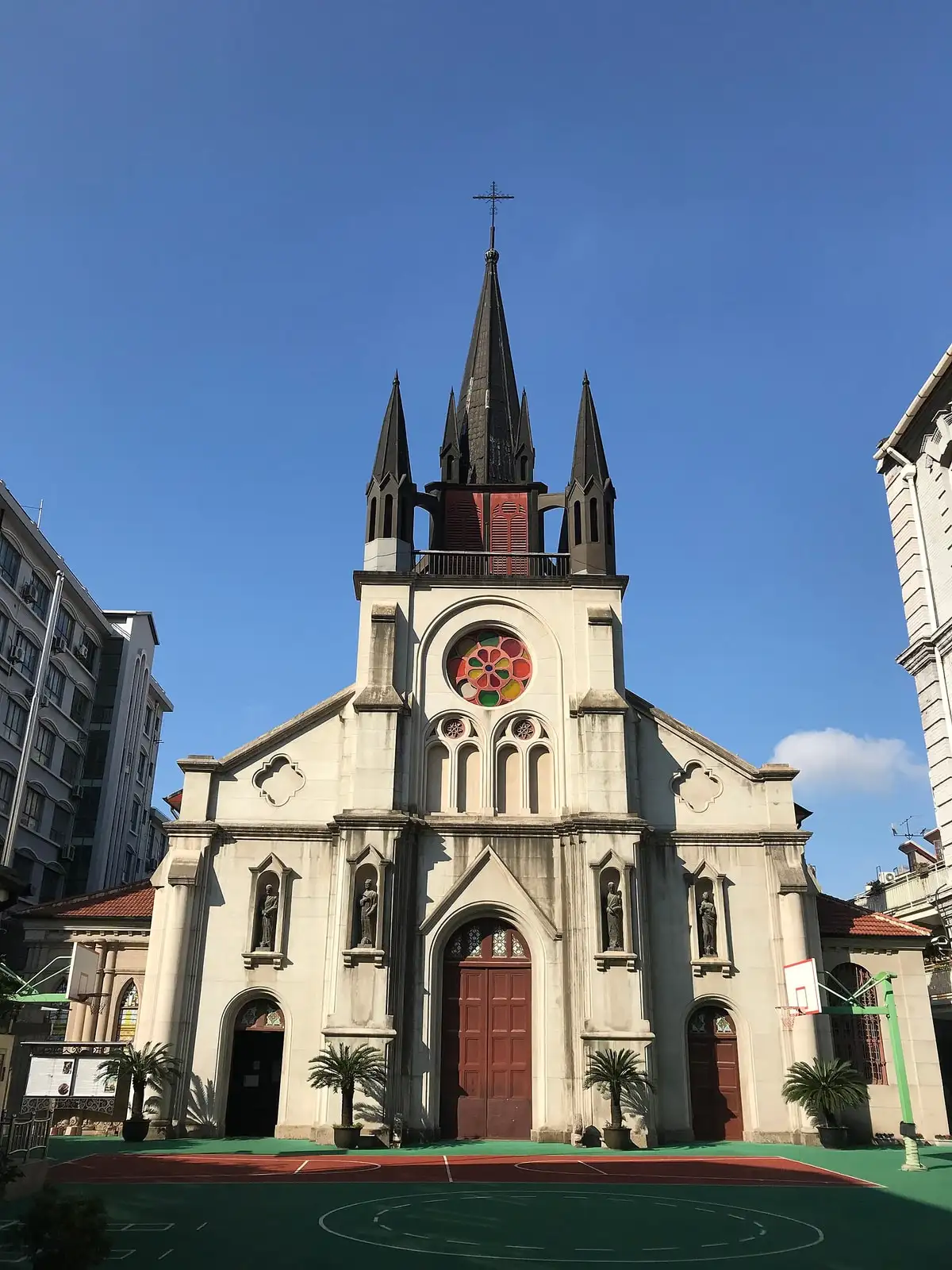 The front of St. Joseph's Church on South Sichuan Road, with a central clock and pointed spire.