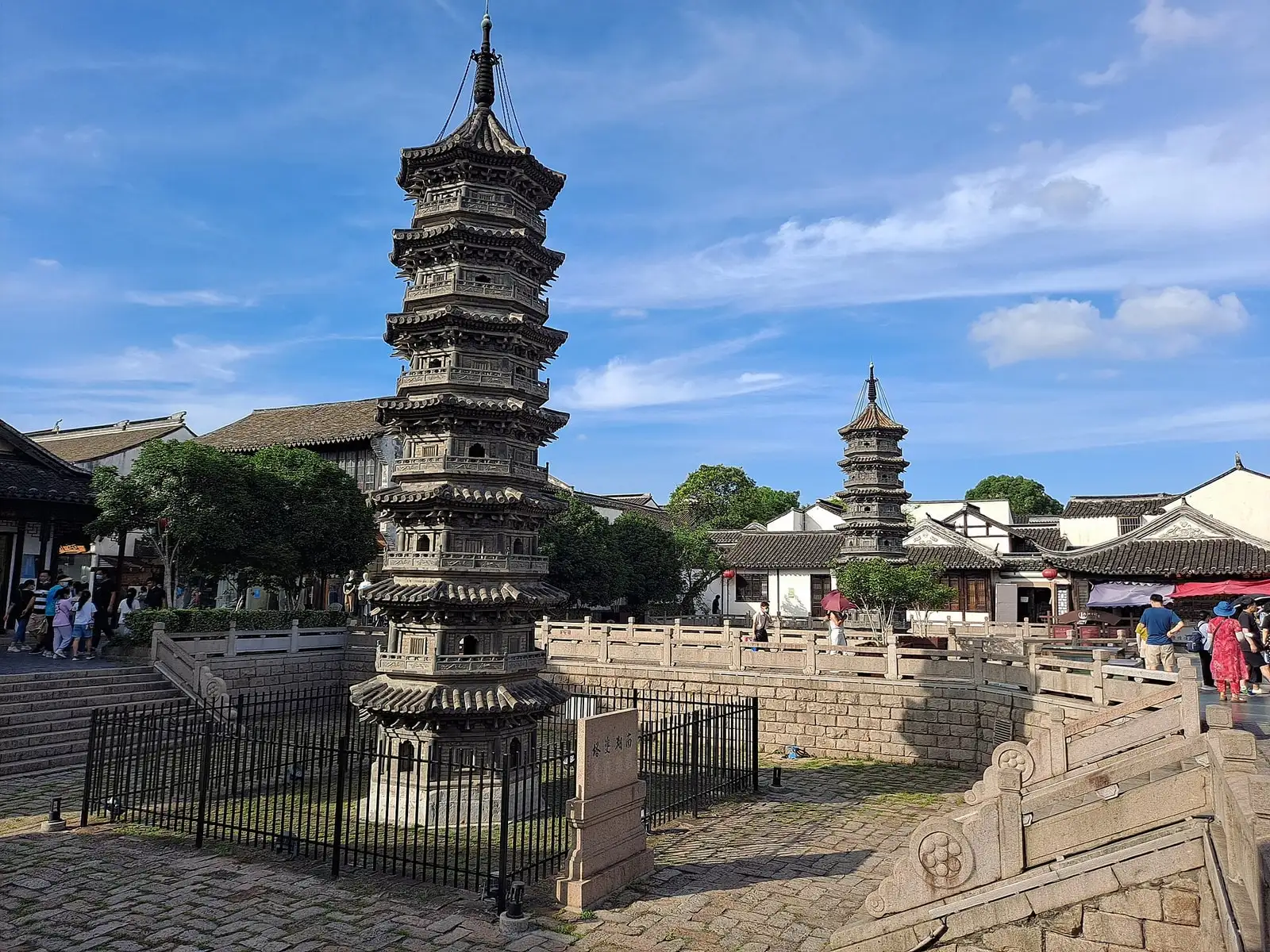 Nanxiang's twin stone pagodas beside a paved street, with tiled roofs beyond.